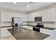 Modern kitchen with white cabinets, stainless steel appliances, and a dark countertop island at 24220 W Ripple Rd, Buckeye, AZ 85326