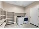 Bright laundry room with tile floor, storage shelves, and modern washer and dryer at 24220 W Ripple Rd, Buckeye, AZ 85326