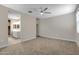 Spacious main bedroom leading to the en-suite bathroom features carpet flooring and a ceiling fan at 24220 W Ripple Rd, Buckeye, AZ 85326