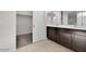 View of a bathroom with a double sink vanity with dark cabinets and an open closet with carpeted floors at 2524 N Pony Ln, Casa Grande, AZ 85122