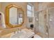 Elegant bathroom with a gold framed mirror, travertine countertop, and glass shower enclosure at 3109 W Summit Walk Ct, Anthem, AZ 85086