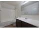 Well-lit bathroom features a shower-tub combo and a vanity with dark wood cabinets at 3111 W Pleasant Ln, Phoenix, AZ 85041