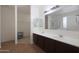 This bathroom features a double vanity sink with dark cabinets, a large mirror, and a walk-in closet at 3111 W Pleasant Ln, Phoenix, AZ 85041