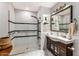 Bright bathroom featuring a glass enclosed shower, vanity with a dark wood cabinet, and marble flooring at 3702 E Camelback Rd, Phoenix, AZ 85018