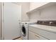 This laundry room includes a door to the exterior, shelving, a washer, and a dryer at 46072 W Barbara Ln, Maricopa, AZ 85139