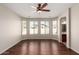 Bright main bedroom showcasing hardwood floors, a ceiling fan, bay windows, and access to the bathroom at 46072 W Barbara Ln, Maricopa, AZ 85139