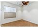 Bright bedroom with neutral carpet features a ceiling fan and large window with blinds at 6508 N 28Th St, Phoenix, AZ 85016