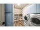 Well-equipped laundry room with blue cabinetry, storage shelves, and modern washer and dryer units at 737 E Boston St, Gilbert, AZ 85295