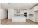 A modern, all-white kitchen with a spacious island, stainless steel appliances, and tile backsplash at 7400 W Quail Track Dr, Peoria, AZ 85383