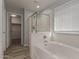 Bathroom featuring a bathtub with a glass shower door, a window with blinds, and wood-style flooring at 9413 W Pioneer St, Tolleson, AZ 85353