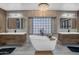 Bright bathroom featuring dual sinks, a soaking tub, and stylish tilework with a statement chandelier at 1001 N 165Th Ave, Goodyear, AZ 85338