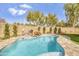 Backyard pool with rock feature surrounded by a block fence and lush greenery at 1001 N 165Th Ave, Goodyear, AZ 85338