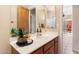 Well-lit bathroom with wood cabinets, a decorative mirror, and outdoor views at 11489 N 141St St, Scottsdale, AZ 85259