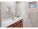 Bathroom with a white sink, decorative oval mirror, a wooden cabinet, and a window with natural light at 11489 N 141St St, Scottsdale, AZ 85259