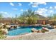 Lush backyard oasis with a freeform pool, rock waterfall, desert landscaping, and outdoor television at 11489 N 141St St, Scottsdale, AZ 85259