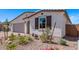 Attractive home exterior with desert landscaping, featuring flowering plants, decorative stone, and a stylish window shutter at 12374 W Marguerite Ave, Avondale, AZ 85323
