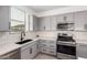 Well-lit kitchen features gray cabinetry, stainless steel appliances, and tile backsplash at 14377 W Alameda Rd, Surprise, AZ 85387