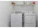 Bright laundry room with a white washer and dryer and open shelving at 14377 W Alameda Rd, Surprise, AZ 85387