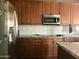 Kitchen featuring wood cabinetry, stainless steel appliances, and a light granite countertop at 14435 W Verde Ln, Goodyear, AZ 85395