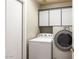 Functional laundry room equipped with a washer, dryer, and overhead storage cabinets for convenience and organization at 15377 W Cheery Lynn Rd, Goodyear, AZ 85395