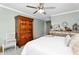 Charming bedroom features rustic wood armoire, ceiling fan, and soothing light green walls at 15563 W Roanoke Ave, Goodyear, AZ 85395