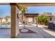 Lounge chairs sit underneath a pergola, overlooking a stone walkway, desert landscaping, and a serene backyard pool at 16438 W Mescal St, Surprise, AZ 85388