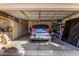 Garage features a blue SUV parked inside, along with built-in storage cabinets and shelving for organized storage at 16438 W Mescal St, Surprise, AZ 85388