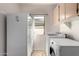 Bright laundry room featuring a white washer, dryer, utility sink, and cabinet storage above, offering functionality at 16438 W Mescal St, Surprise, AZ 85388