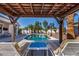 Relaxing poolside view featuring lounge chairs under a wooden pergola, overlooking a lush garden, and crystal-clear swimming pool at 16438 W Mescal St, Surprise, AZ 85388