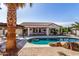 Stunning backyard pool, complemented by a covered patio, lush palm trees, and comfortable lounge chairs at 16438 W Mescal St, Surprise, AZ 85388