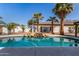 Beautiful swimming pool with a rock waterfall feature, surrounded by lush landscaping and tall palm trees at 16438 W Mescal St, Surprise, AZ 85388