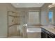 Bathroom featuring a glass enclosed shower and separate soaking tub near a window at 16881 W Monroe St, Goodyear, AZ 85338