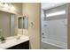 Clean bathroom featuring a vanity with a dark wood cabinet, a mirror, and a shower-tub combo at 16881 W Monroe St, Goodyear, AZ 85338