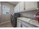 Laundry room featuring modern washer/dryer, white cabinets, sink, and natural light at 19051 N 259Th Ave, Buckeye, AZ 85396