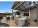 Outdoor kitchen with stainless grill and bar seating under a pergola, overlooking a pool at 19051 N 259Th Ave, Buckeye, AZ 85396