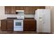 Traditional kitchen featuring brown cabinets, dark countertops, and white appliances at 2146 E Aloe Pl, Chandler, AZ 85286