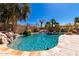 Backyard pool with a rock waterfall feature and mature palm trees creating a private oasis at 22139 N 80Th Ln, Peoria, AZ 85383