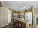 A warm kitchen featuring an island with bar seating, light wood cabinets, and modern appliances at 22346 N Goles Dr, Maricopa, AZ 85138