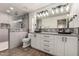 Well-lit bathroom with white cabinets, dual sinks and framed mirrors; tiled shower and plank flooring at 2415 Leisure World --, Mesa, AZ 85206