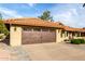 Tan stucco home showcasing a wooden garage door and a red tile roof against a blue sky at 2415 Leisure World --, Mesa, AZ 85206