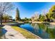 Scenic pond with lush landscaping and a paved walking path under a clear blue sky at 2415 Leisure World --, Mesa, AZ 85206