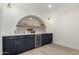 Stylish bar area with navy cabinets, a wine fridge, and an arched display niche with a wooden shelf at 25620 S Cloverland Dr, Sun Lakes, AZ 85248