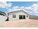 A view of the house's backyard featuring large windows, stucco siding, and a spacious dirt-filled lot with block wall fencing at 2707 E Abe Truckle Ave, San Tan Valley, AZ 85140