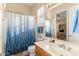 Bright bathroom with a white vanity, shower with blue-white curtain, and natural light at 2838 E Vaughn Ct, Gilbert, AZ 85234