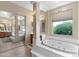 Bathroom featuring soaking tub with a window view, dual vanities, and step-up access through mirrored doors at 2838 E Vaughn Ct, Gilbert, AZ 85234