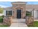 Elegant stone facade frames a custom metal front door, accented by manicured shrubs and stone accents at 2838 E Vaughn Ct, Gilbert, AZ 85234