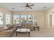 Bright living room featuring tan sofas, a ceiling fan and lots of natural light through the window at 2838 E Vaughn Ct, Gilbert, AZ 85234