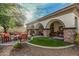 Inviting backyard patio with stone columns, lush green grass, and cozy seating area with orange cushioned chairs at 3080 E Palmdale Ln, Gilbert, AZ 85298