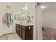 Well-lit bathroom with double vanity, framed mirror and access to an adjacent closet and bedroom at 3080 E Palmdale Ln, Gilbert, AZ 85298