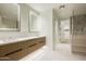 Bathroom with double vanity, backlit mirrors, tiled floors, and glass-enclosed shower at 5000 N Camelback Ridge Rd # 410, Scottsdale, AZ 85251